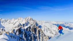 Skier skiing down the mountain under a blue sky