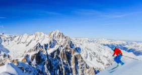 Skier skiing down the mountain under a blue sky