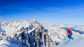 Skier skiing down the mountain under a blue sky
