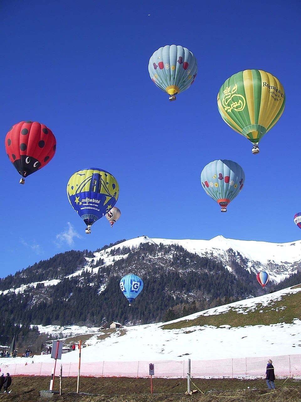 Hot air balloons flying over the snow-covered landscape of Château-d'Œx